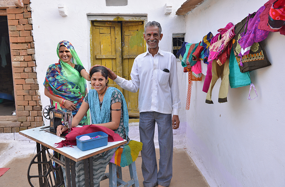 Eine junge Frau mit ihren Eltern, die dank einer Nähausbildung selbständig arbeiten kann in Aparajita, Indien