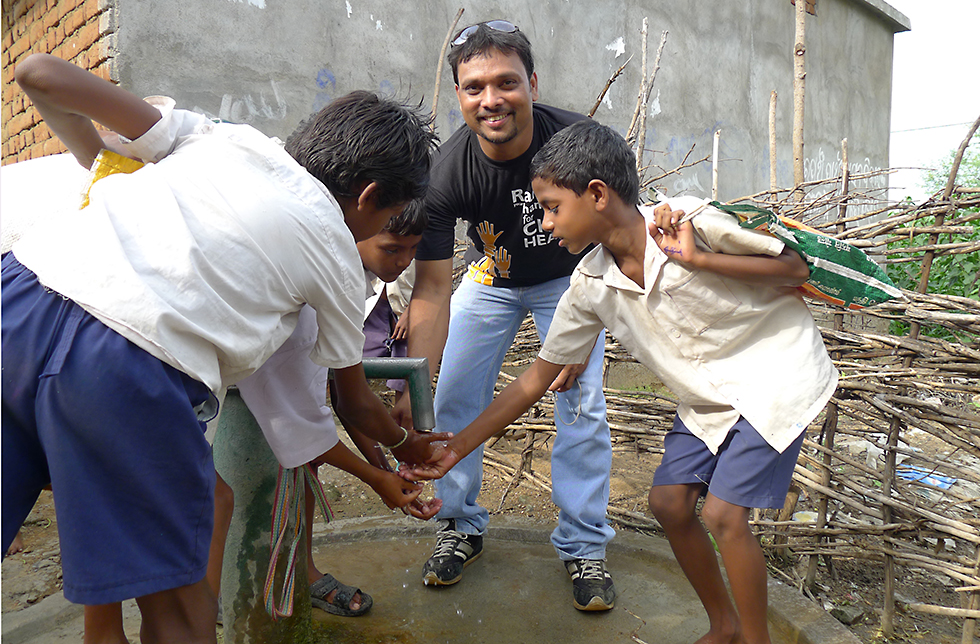 Kinder waschen sich die Hände in Khariar, Indien