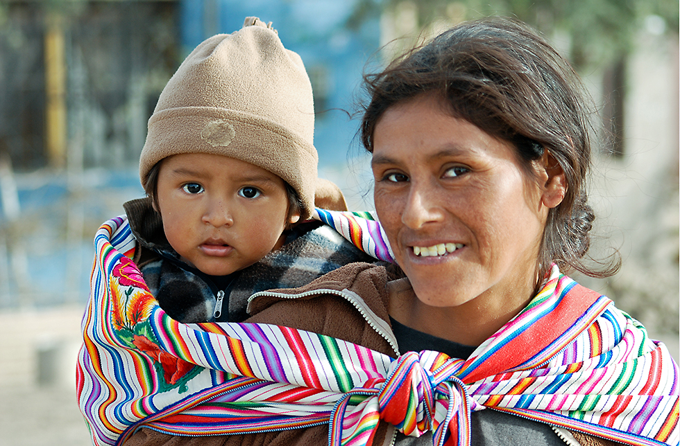 Eine Mutter trägt ihr Kind auf dem Rücken in Mancos, Peru 